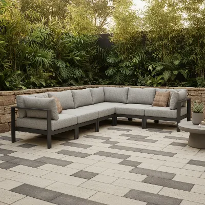 A modern L-shaped outdoor sectional sofa on a spacious patio with lush greenery.